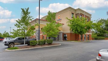 A Comfort Inn hotel with a brick facade, a parking lot, and a few trees in front.