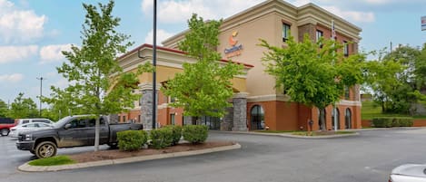 A Comfort Suites hotel with a brick facade, a parking lot, and a street view.