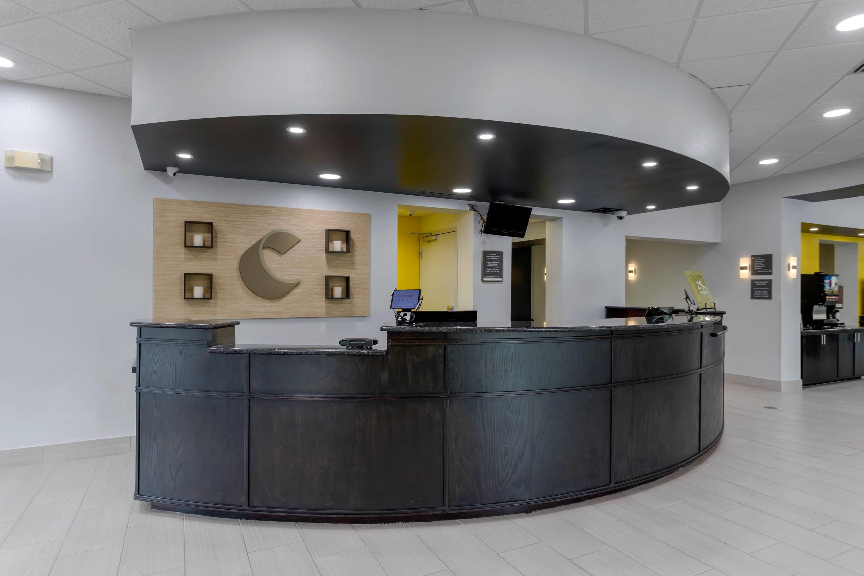 A reception area with a curved reception desk, a wall-mounted clock, and a security camera.