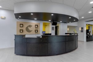 Un'area reception con una scrivania a forma di arco, un orologio a parete e una telecamera di sicurezza.