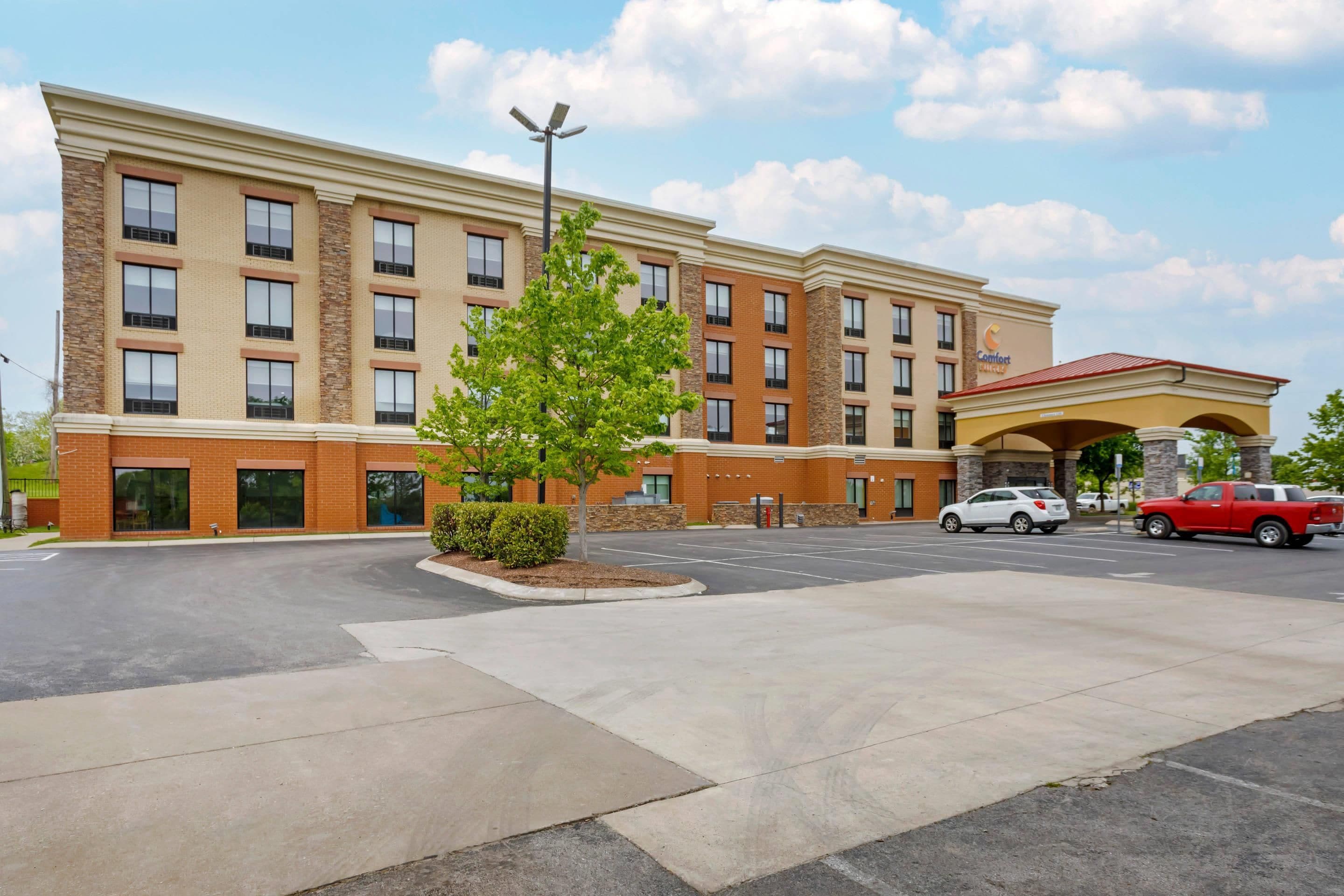 A multi-story hotel with a parking lot and a covered entrance.