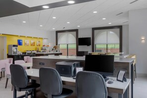 Un espacio de oficina moderno con área de recepción, una barra con cafetera y un amplio ventanal con vistas.