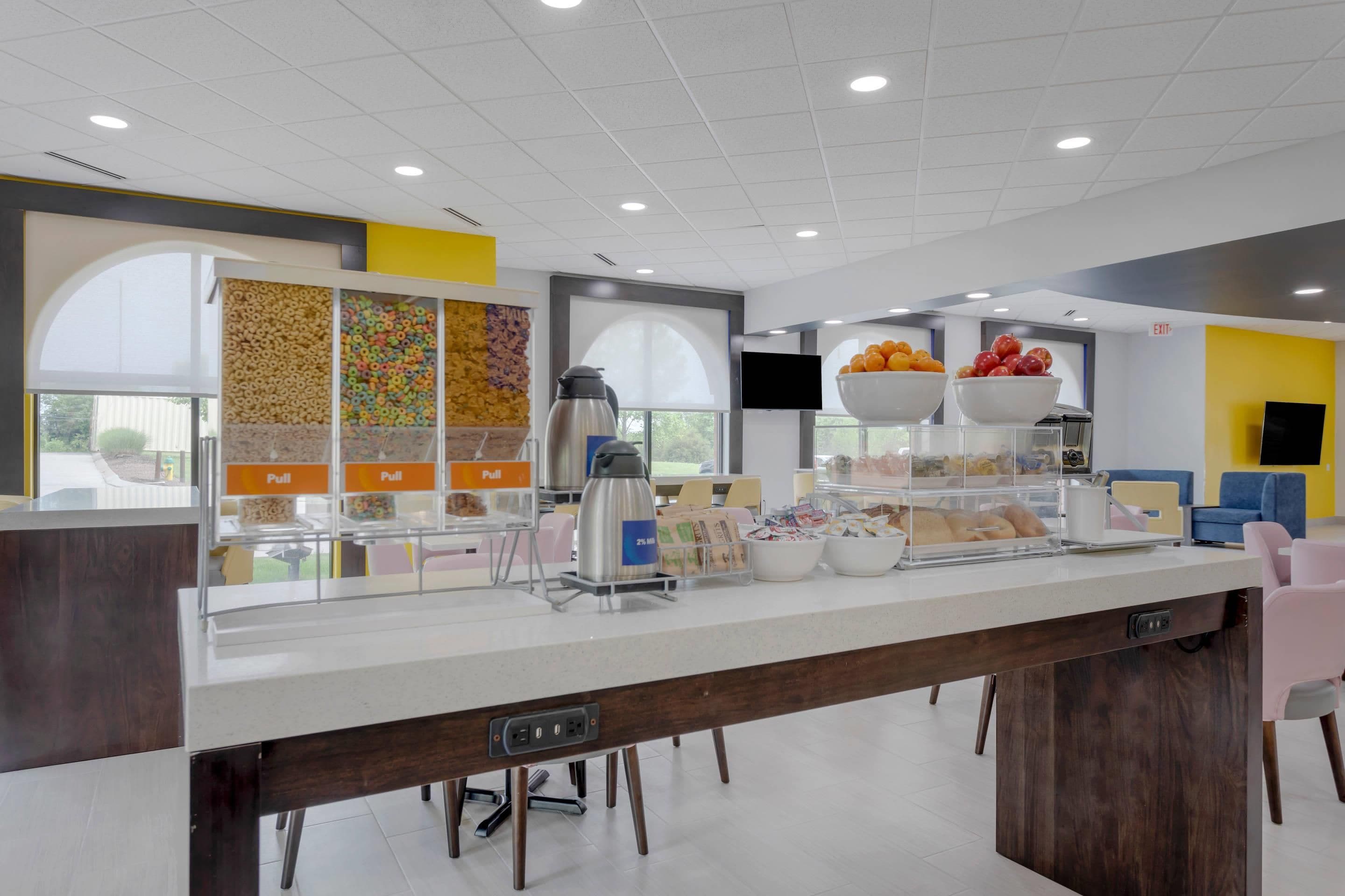 Una barra de desayuno moderna con diversas opciones de comida, una máquina de café y zonas de estar.