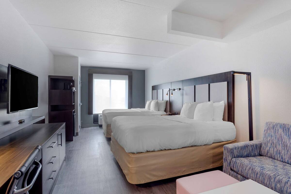 A modern hotel room with a large bed, a TV, a desk, and a sofa.