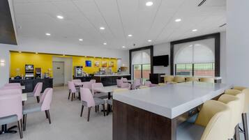 A modern dining area with a central island, multiple seating options, and a bright yellow accent wall.