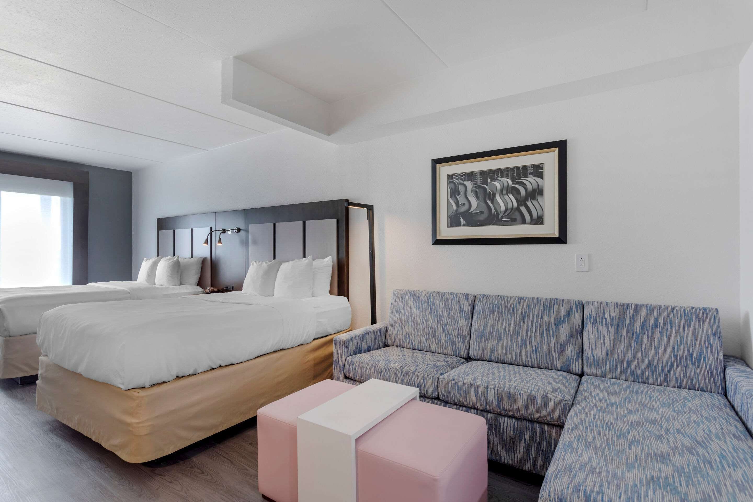 Una habitación de hotel moderna con una cama grande, un sofá y una obra de arte enmarcada en la pared.