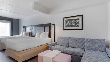Una habitación de hotel moderna con una cama grande, un sofá y una obra de arte enmarcada en la pared.