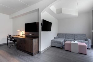 Un dormitorio moderno con escritorio, silla, dos camas y televisor.