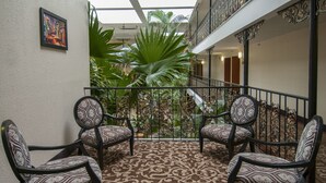 A balcony with patterned chairs, a decorative railing, and lush greenery. - Governor's Suites Hotel Oklahoma City Airport Area (Oklahoma City)