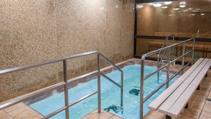 A spa area with a hot tub, metal railings, and a wooden bench. - Governor's Suites Hotel Oklahoma City Airport Area (Oklahoma City)