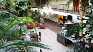 A spacious indoor area with a high ceiling, a chandelier, and a seating area with red sofas. - Governor's Suites Hotel Oklahoma City Airport Area (Oklahoma City)