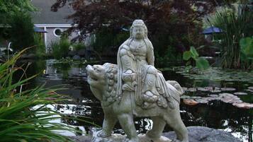 A stone statue of a figure on a horse by a pond.