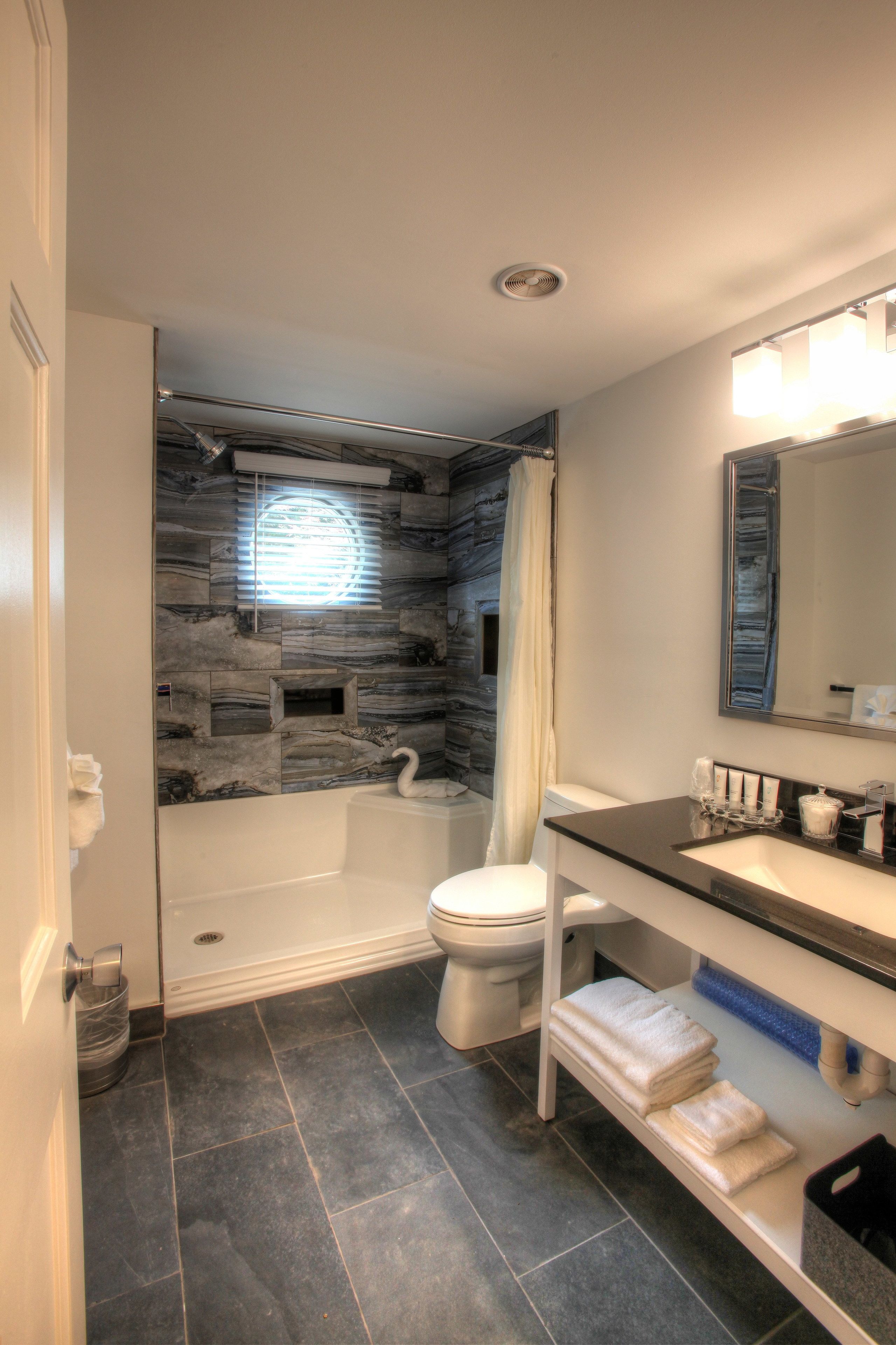 A bathroom with a stone wall, a bathtub, a toilet, and a sink with a mirror.