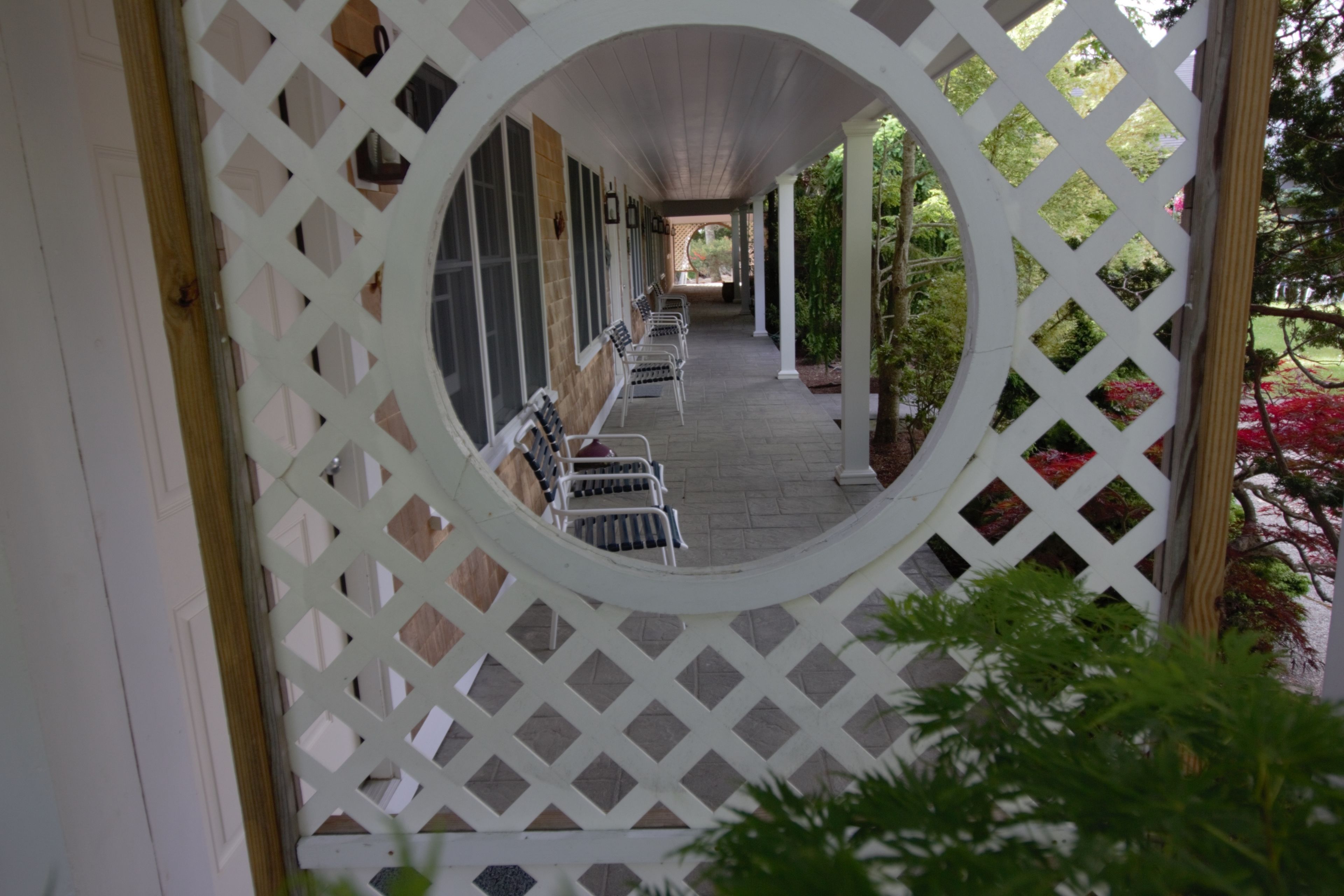 A covered outdoor seating area with a lattice structure, benches, and potted plants.