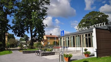 Experience the Arena Hotel's sleek entrance, surrounded by lush greenery and bike-friendly amenities.