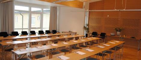 A conference room with long tables, chairs, and a projector.