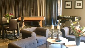 Una sala de estar moderna con un sofá, dos sillones, una mesa de centro, una chimenea y una mesa de fútbol.