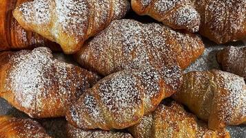 A tray of assorted pastries, including croissants and other baked goods, dusted with powdered sugar.
