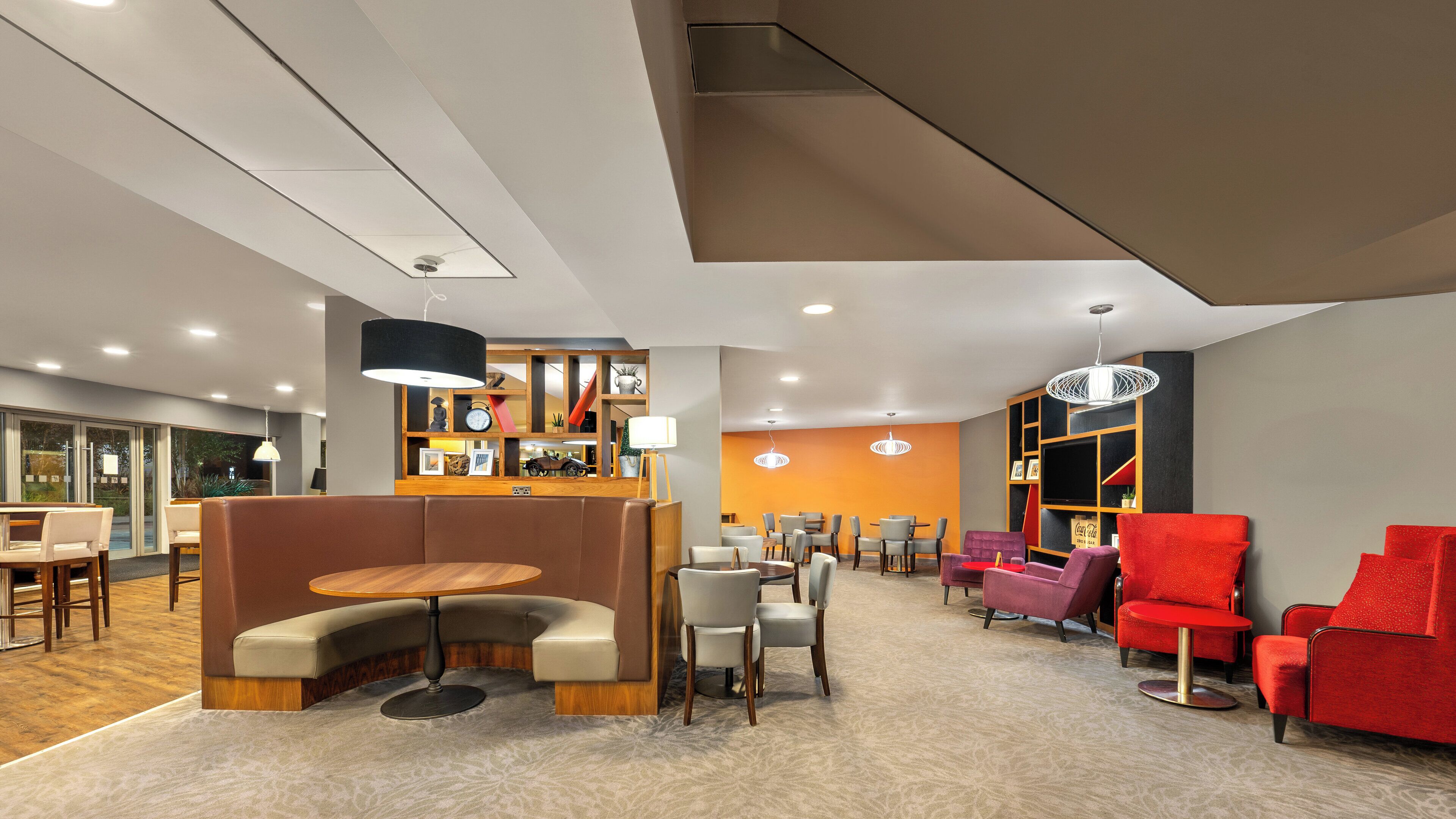 Un espace de détente moderne, doté de sièges confortables, d’un bar et offrant une vue sur l’extérieur.