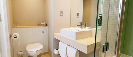 A modern bathroom with a toilet, sink, and glass shower enclosure.
