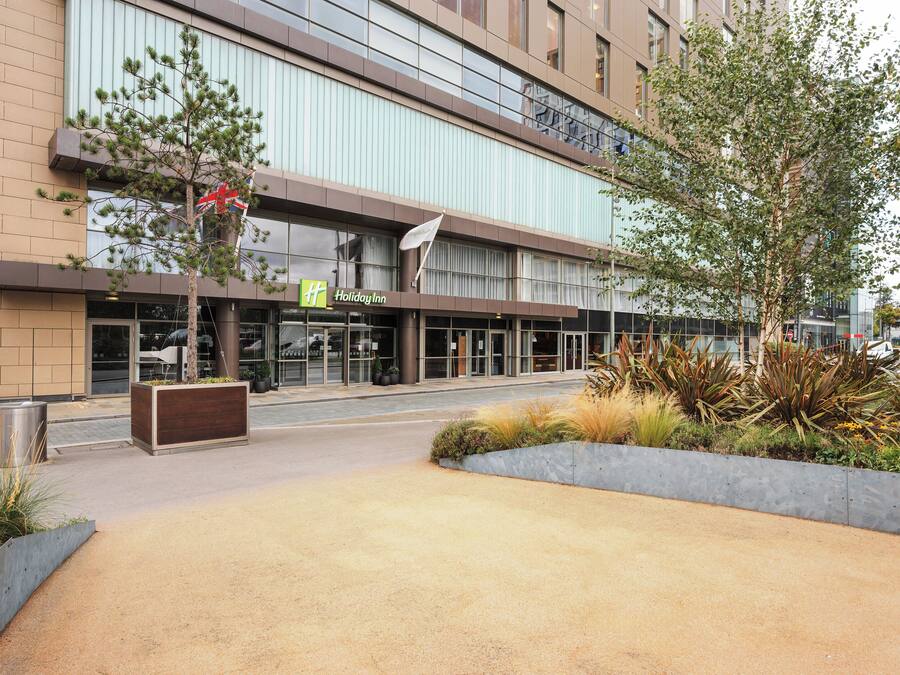 A Holiday Inn hotel with a modern facade, large windows, and a landscaped entrance area.