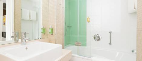 A modern bathroom with a large white sink, a glass-enclosed shower, and a white bathtub.