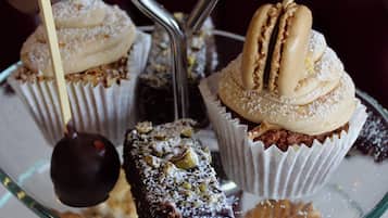 Una presentación de postres con diversos pasteles y dulces sobre un expositor de vidrio.