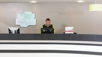 A reception desk with a computer, a sign for the Holiday Inn, and a welcome sign for the HIG Rewards Club.