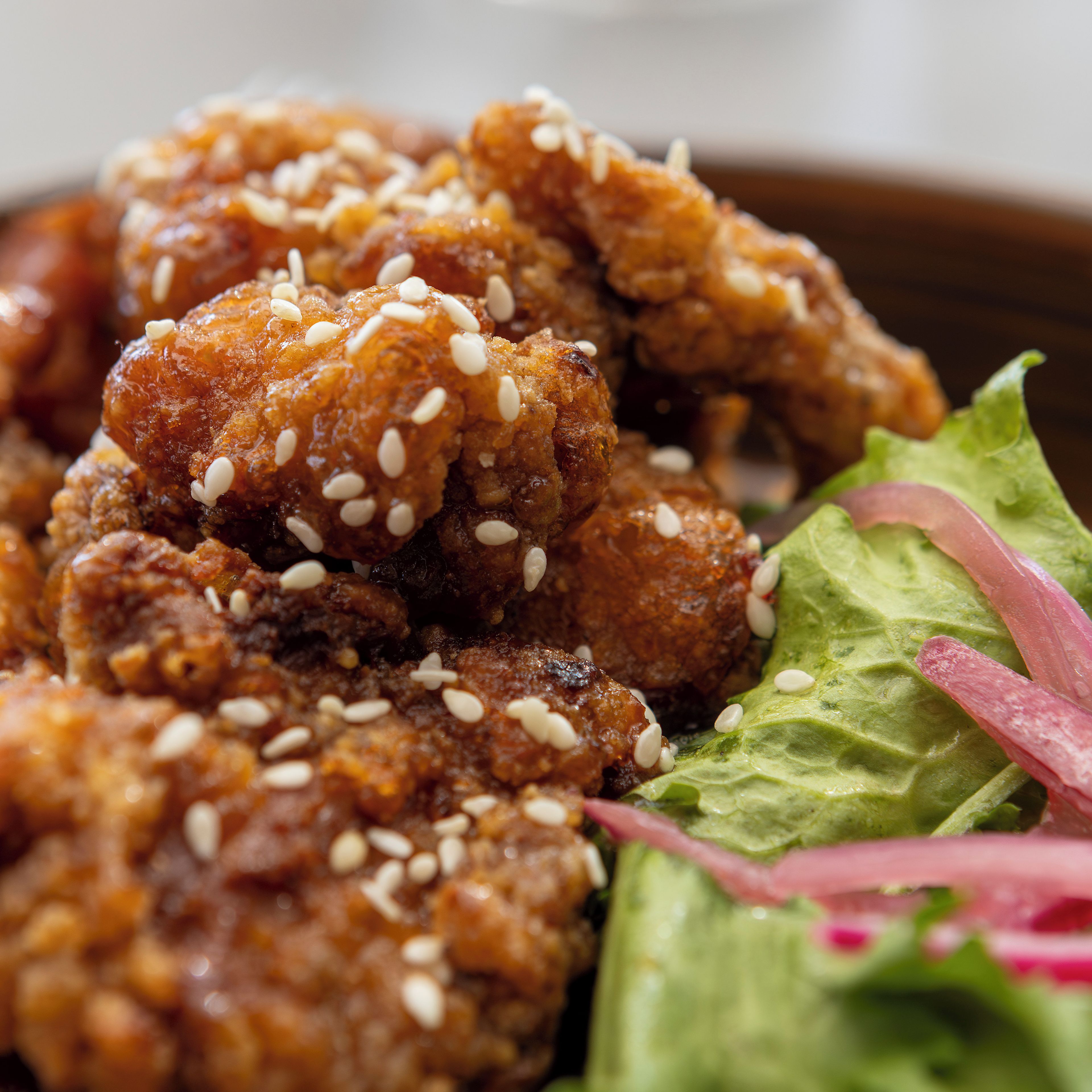 A close-up of a dish with sesame seeds and a side of green lettuce with red onion.