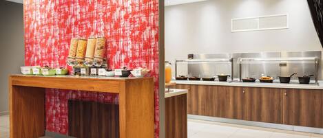 A buffet setup with a wooden table and a red textured wall.