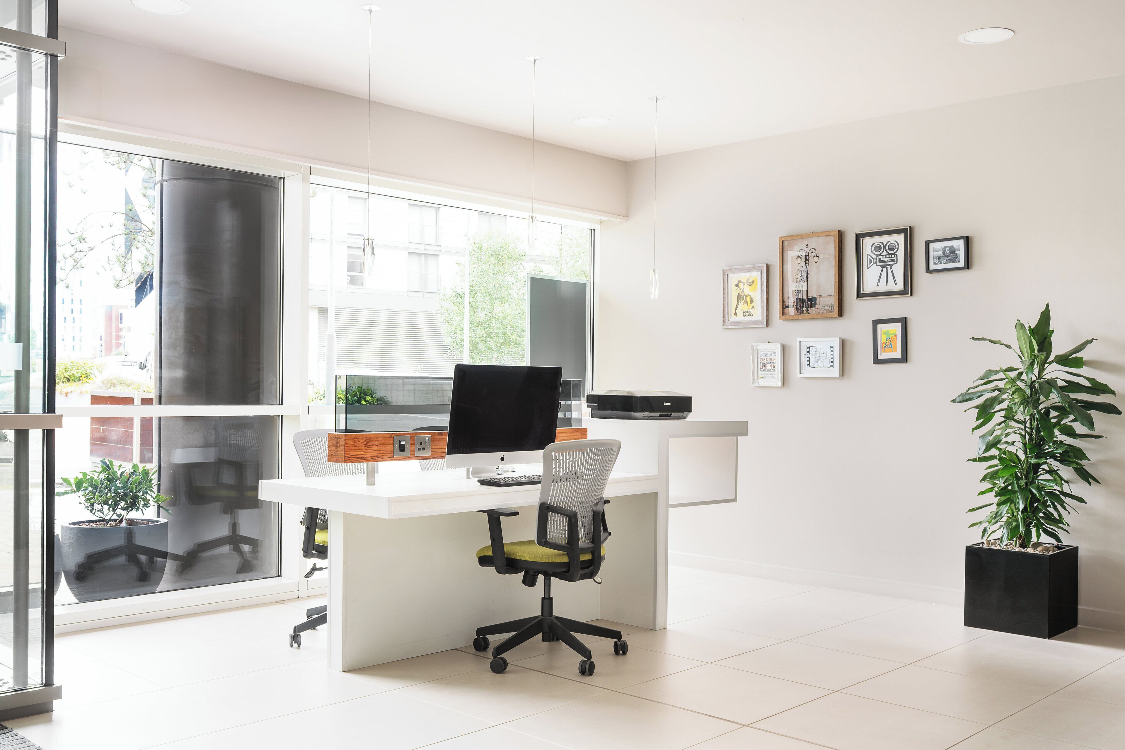 A modern office with a white desk, ergonomic chair, and a large window offering a view of the city.