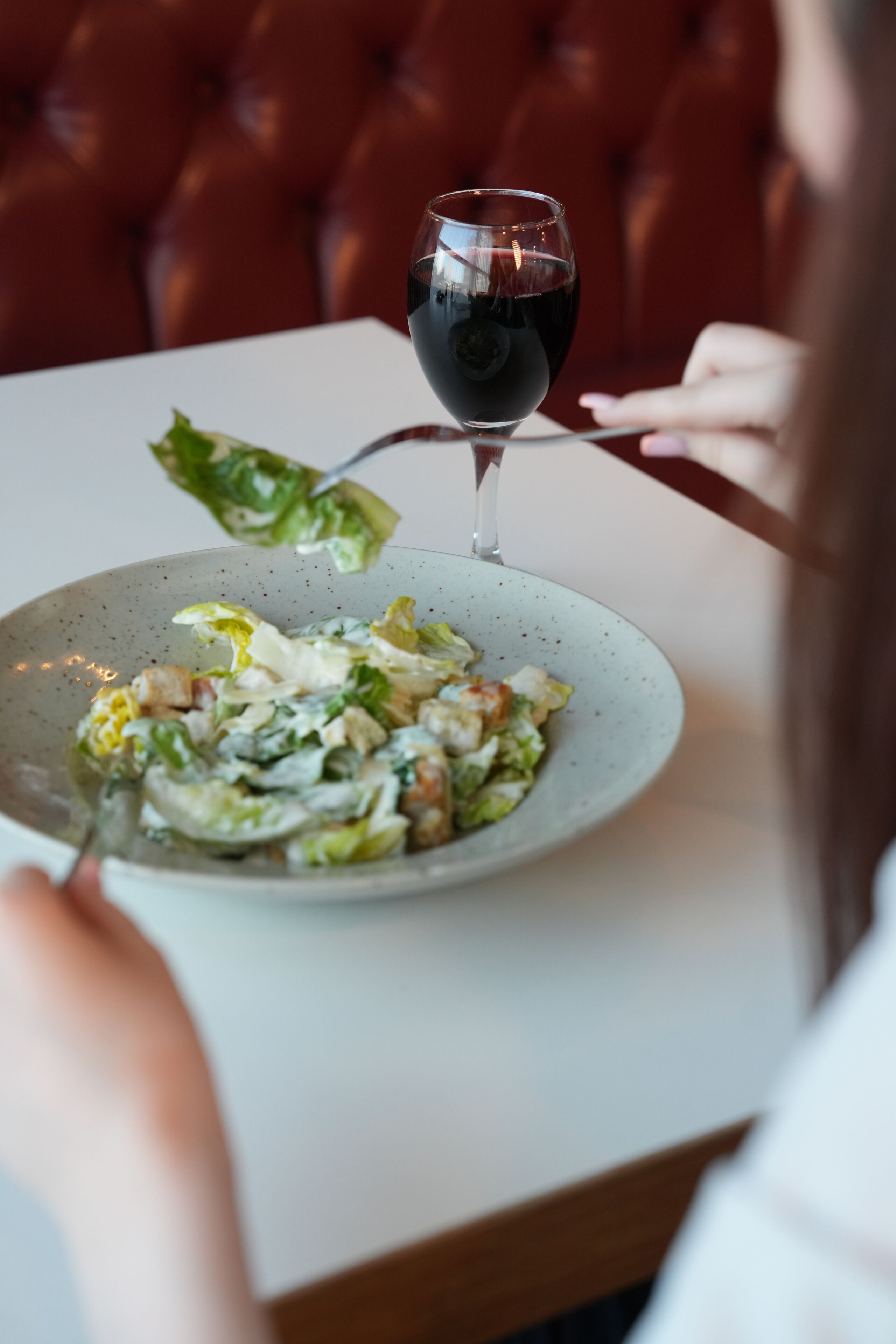 A dining table with a plate of food and a glass of red wine.
