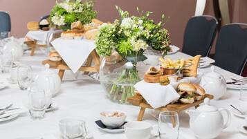 A dining table set with white tablecloths, glassware, and a centerpiece with flowers and bread.