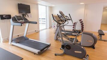 A gym with treadmills, elliptical machines, and a weight bench.