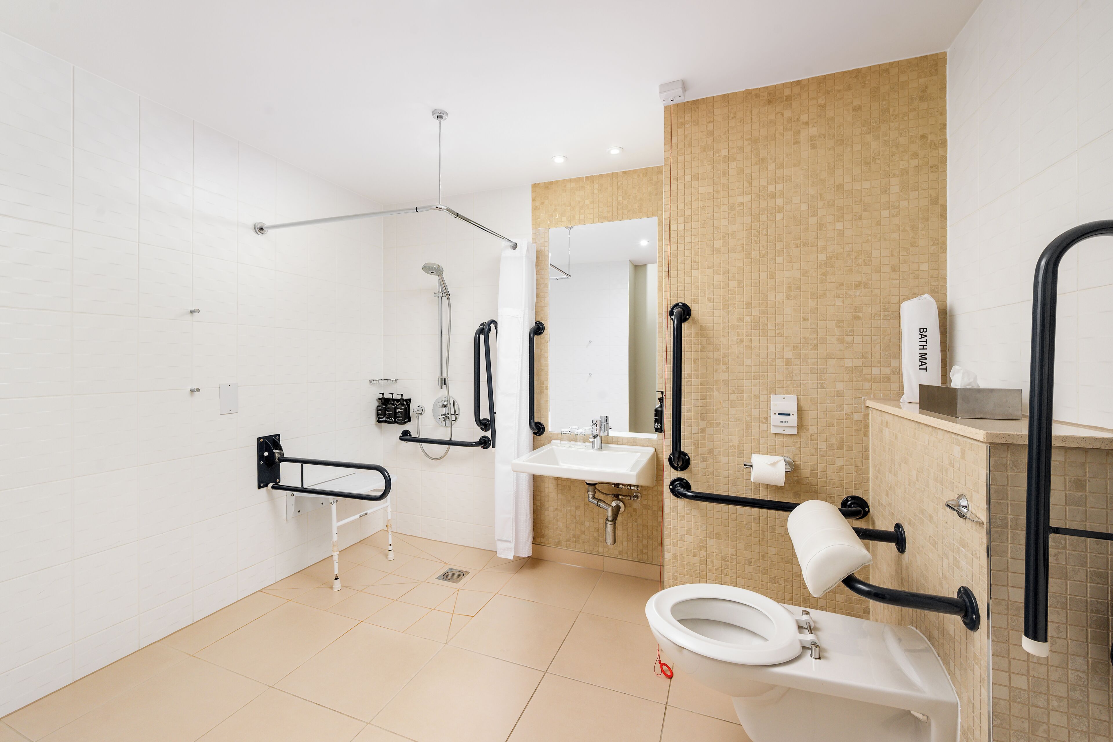 Un baño moderno con inodoro blanco, lavabo y zona de ducha.