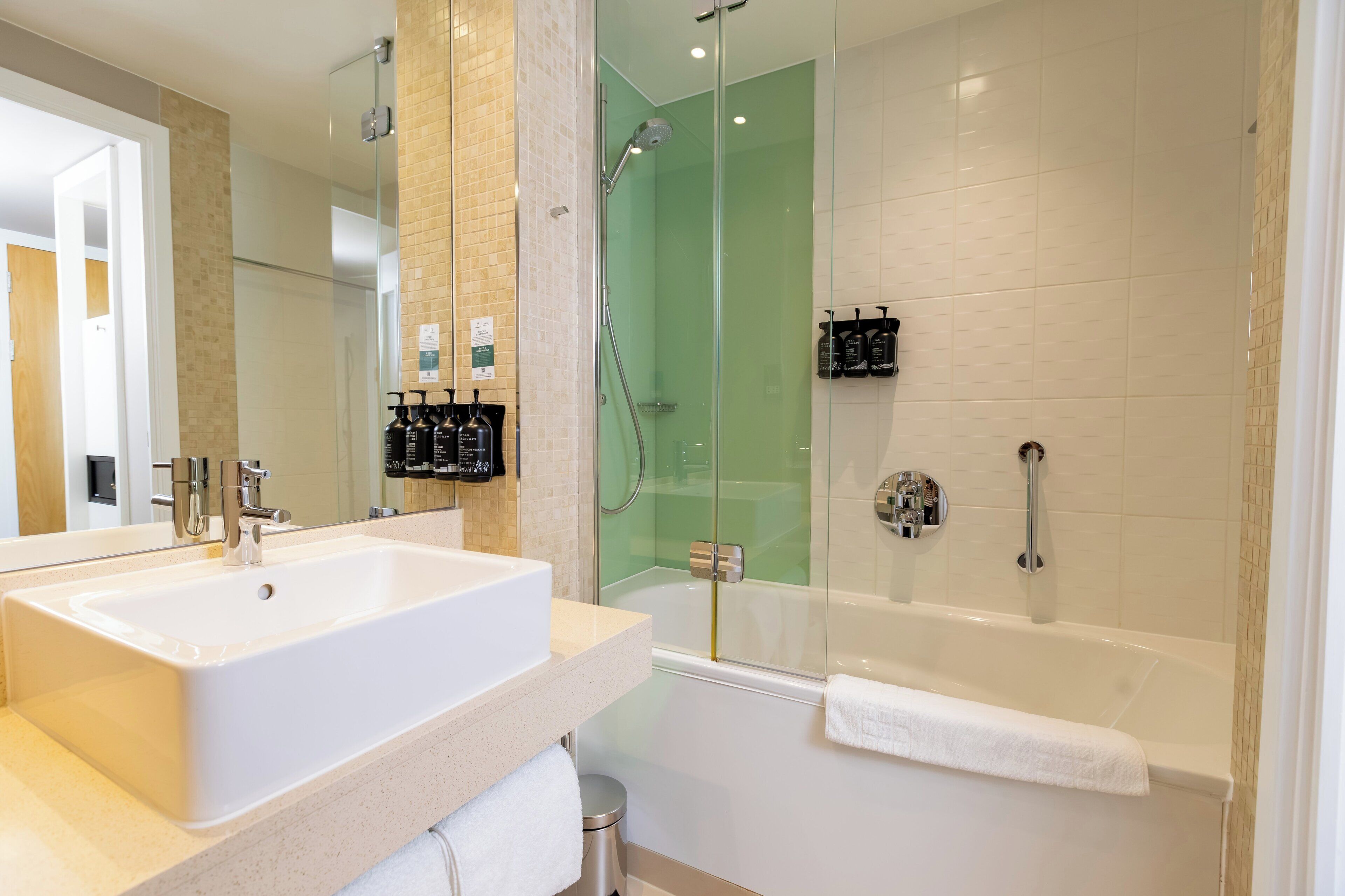 A modern bathroom with a large white sink, a glass-enclosed shower, and a white bathtub.
