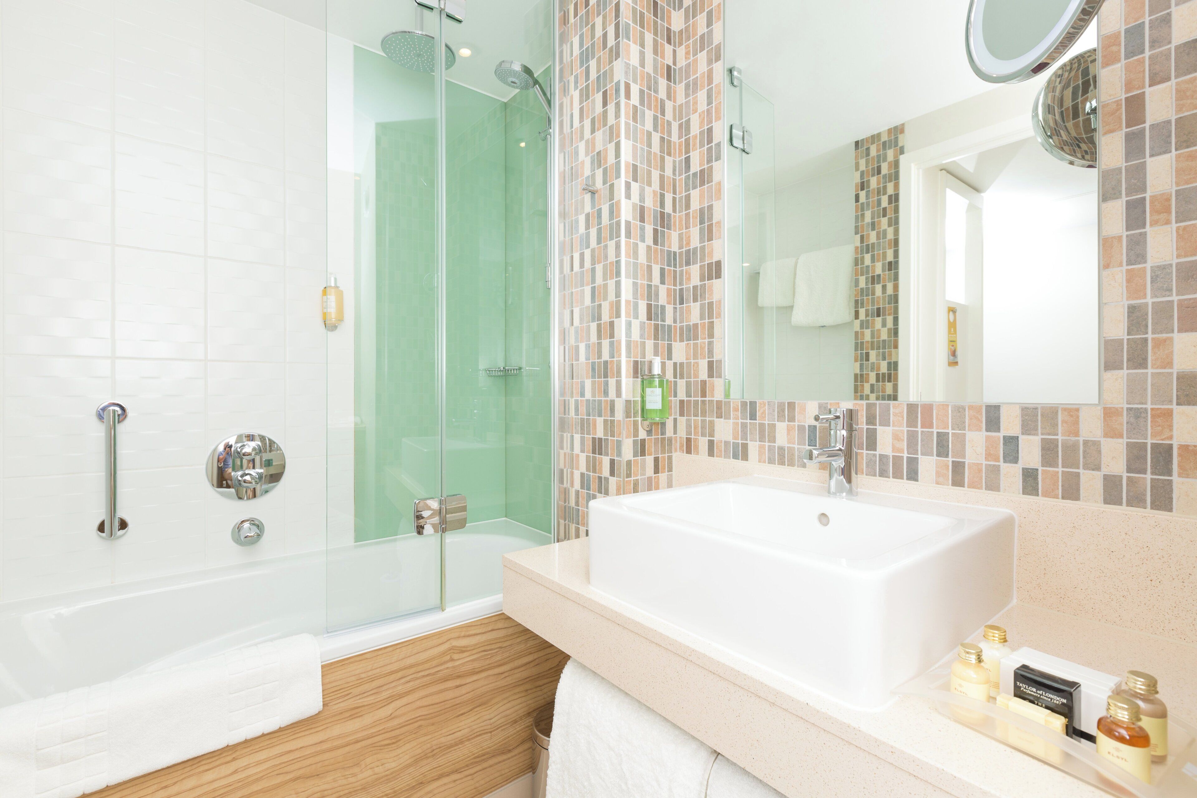 Un baño moderno con cabina de ducha de vidrio, un lavamanos grande y un espejo.