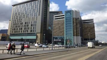 Un hotel moderno con una fachada de vidrio destacada y un letrero que indica 'Booths', señalando un centro de negocios cercano.