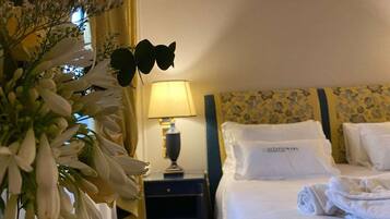 Una habitación de hotel con una cama bien hecha, una lámpara de noche y un arreglo floral.