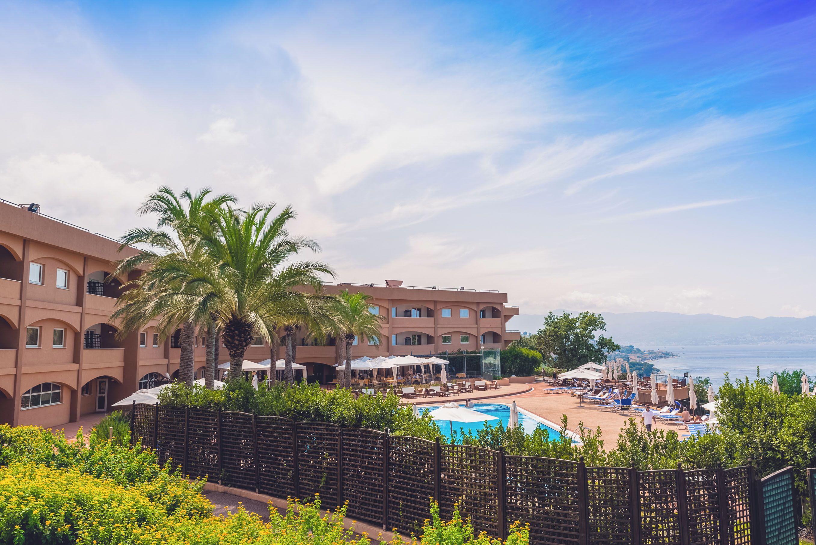Ein Resort mit Pool, Palmen und Meerblick.