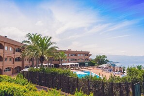A resort with a pool, palm trees, and a view of the sea. - Altafiumara Resort & Spa (Villa San Giovanni)