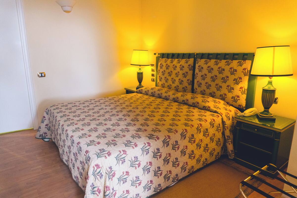 A hotel room with a bed, two bedside tables, and lamps.