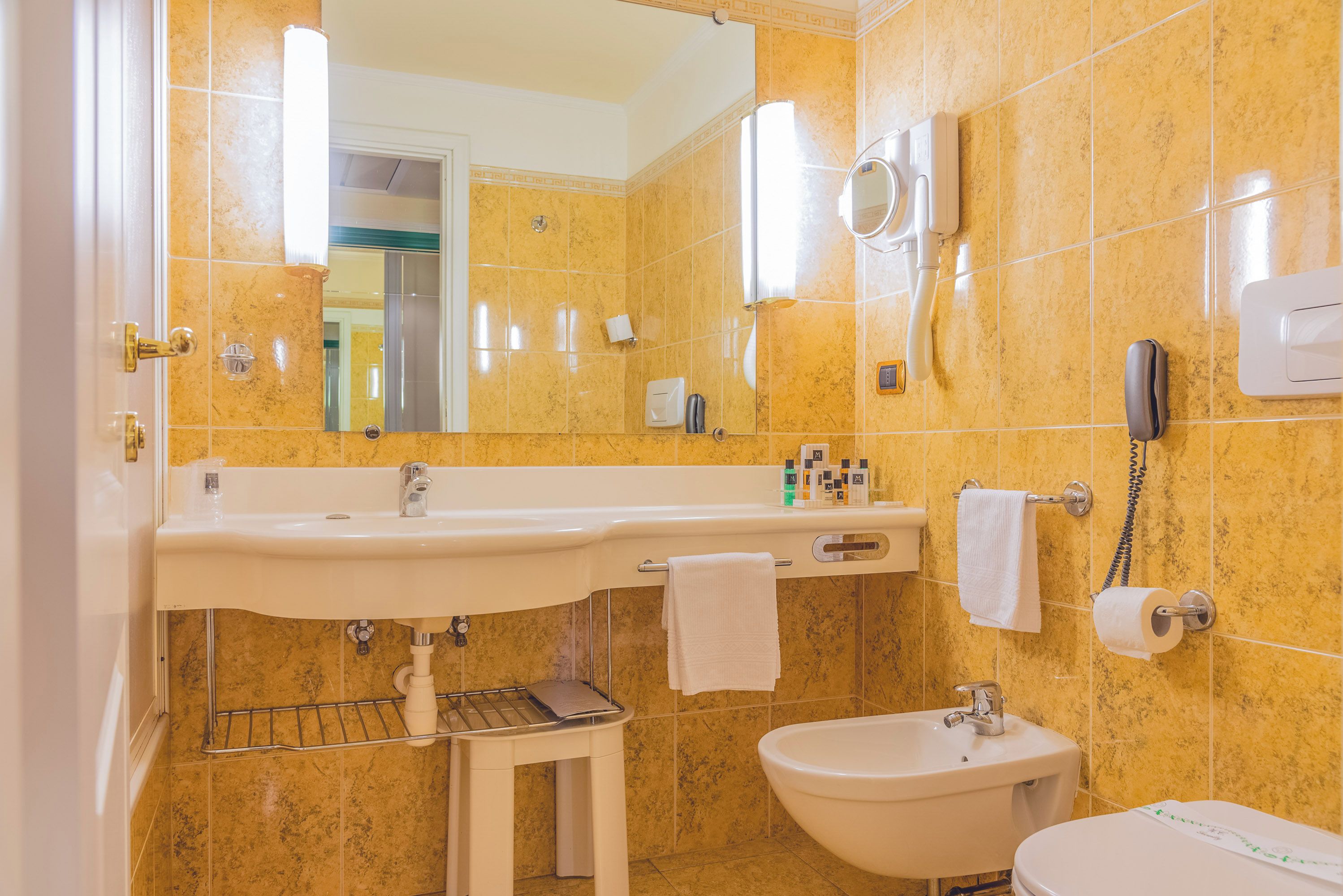 A bathroom with a sink, bidet, and toilet, all with white fixtures.