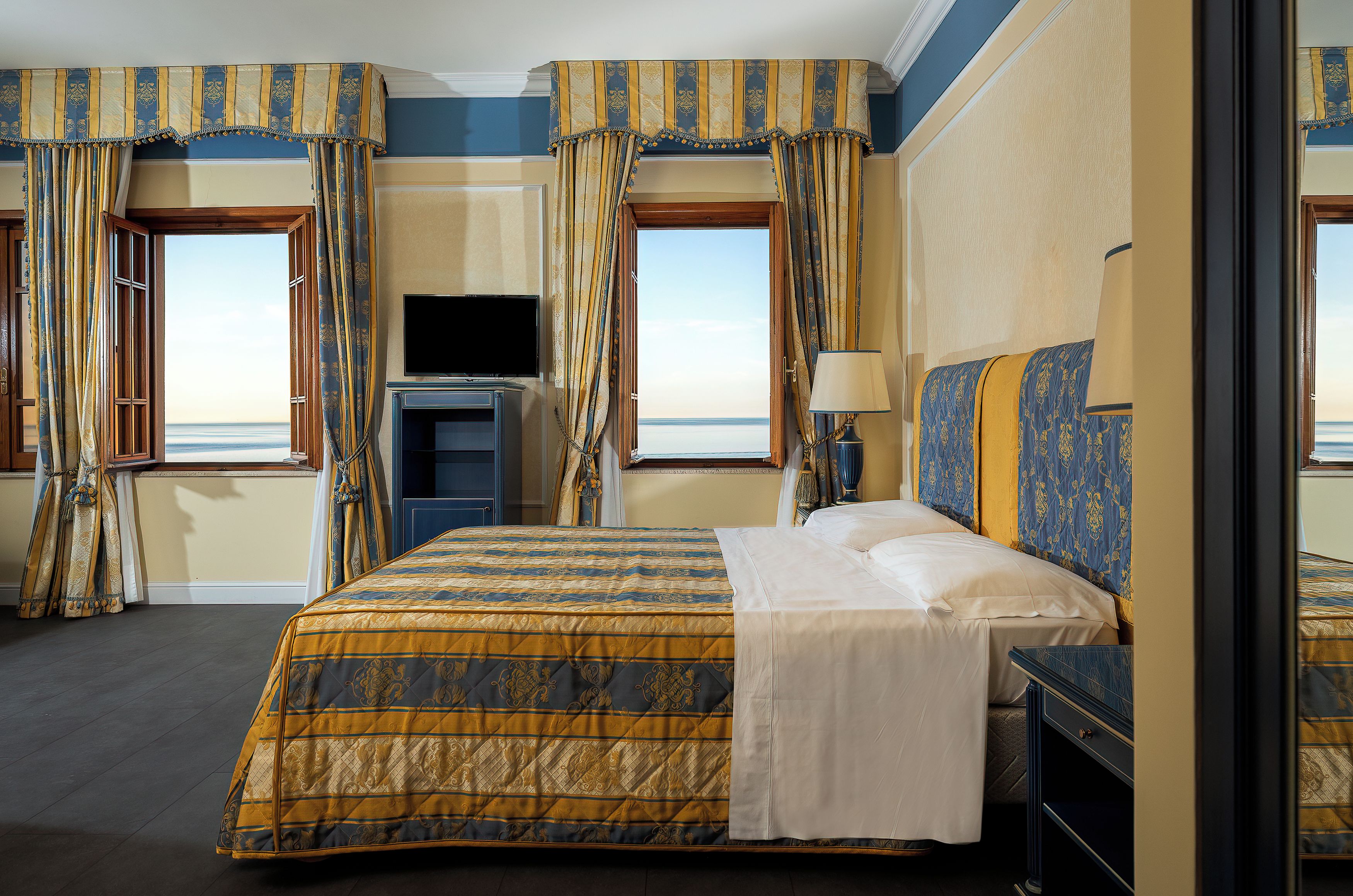 A hotel room with a large bed, a television, and a window with curtains.
