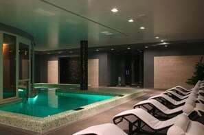 A modern indoor pool area with a clear pool, lounge chairs, and a spa-like ambiance. - Altafiumara Resort & Spa (Villa San Giovanni)