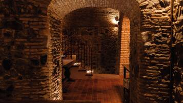 A stone-walled corridor with a wooden bench and a metal railing.