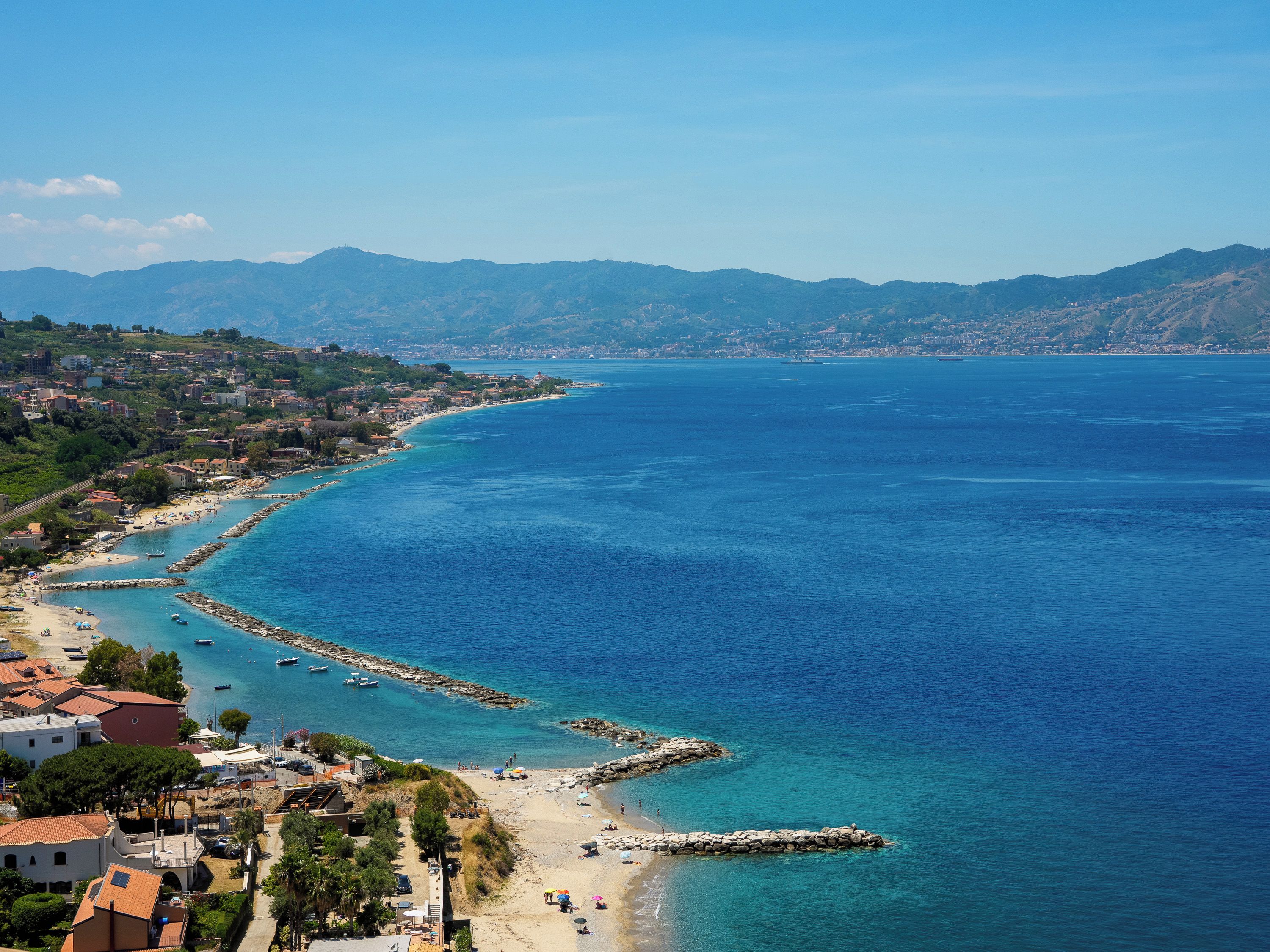 A coastal town with a beach, rocky shoreline, and buildings along the coast.