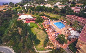 An aerial view of a resort with a swimming pool, lounge areas, and a tennis court. - Altafiumara Resort & Spa (Villa San Giovanni)