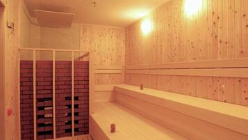 A sauna with wooden walls and benches, a brick wall section, and a ceiling light.