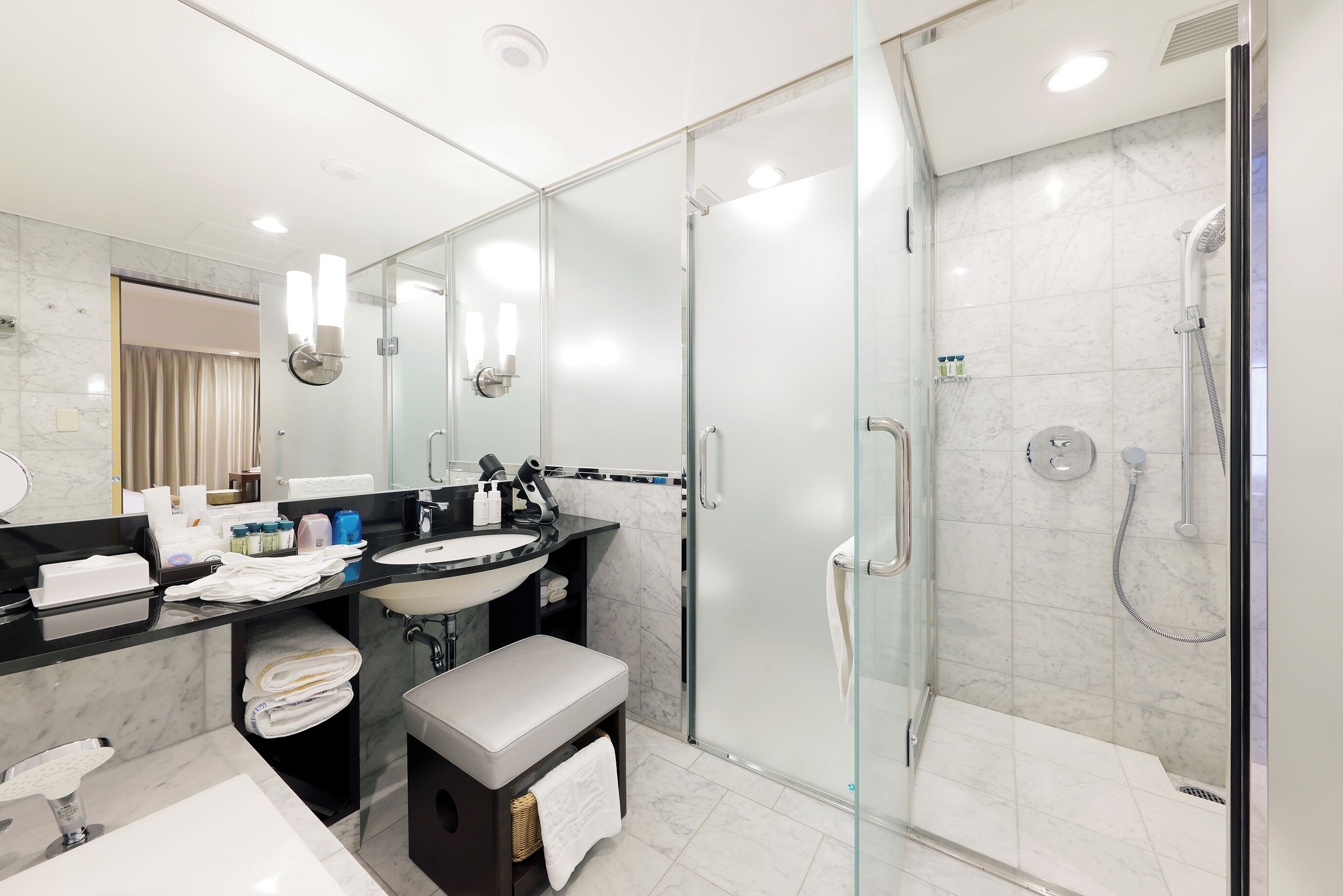 A modern bathroom with a glass-enclosed shower, a vanity with a sink, and a mirror.